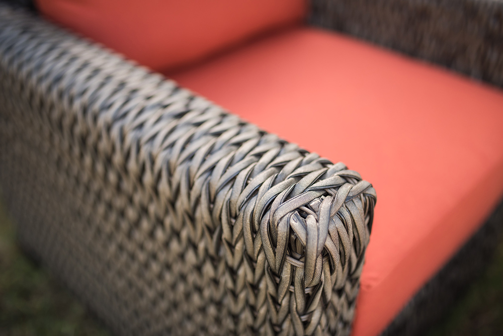 A brown wicker chair with a Fall colored cushion.