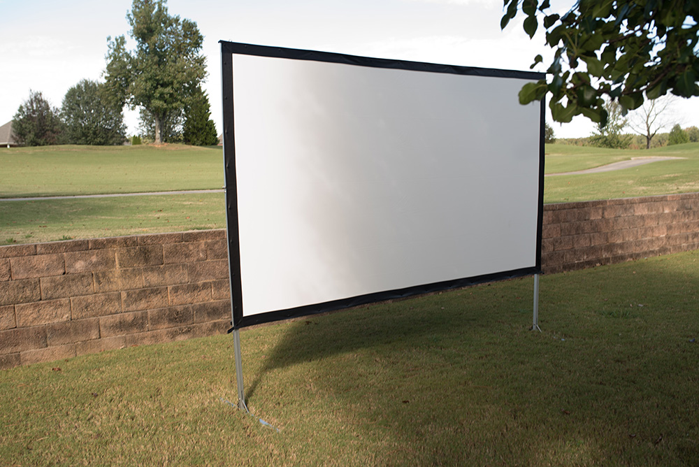 A white projector screen in front of an outdoor wall.