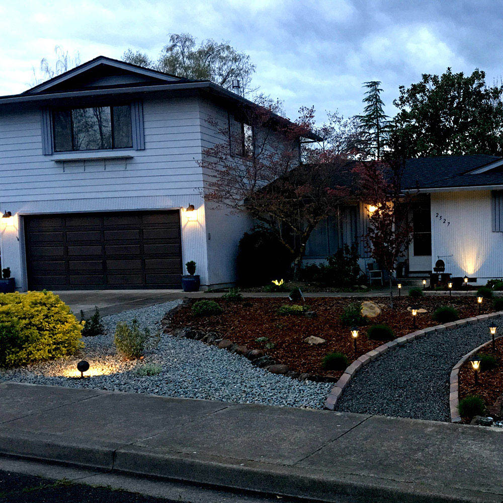 A home is well-lit with outdoor landscape lighting.