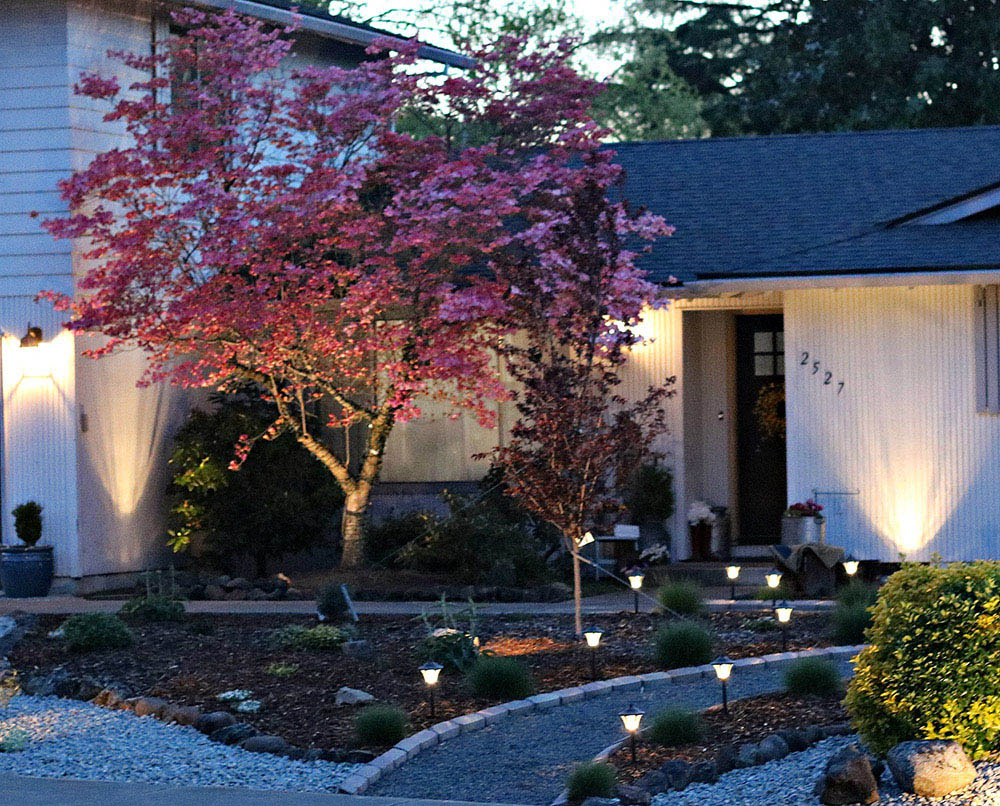 A front yard lit with pathway, spotlights, and flood lights.