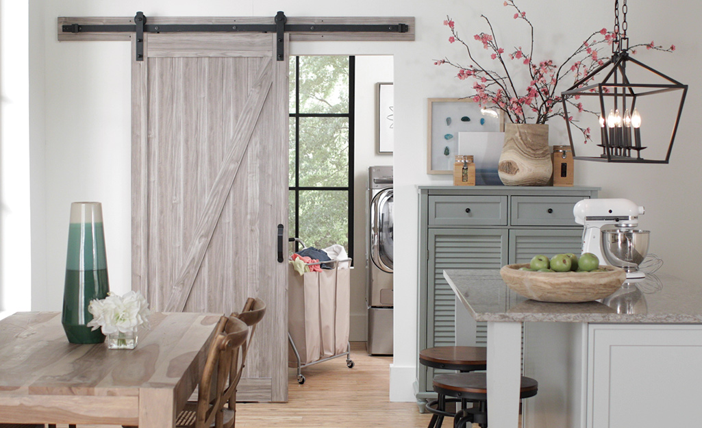 A barn door separating a kitchen from a laundry room. 