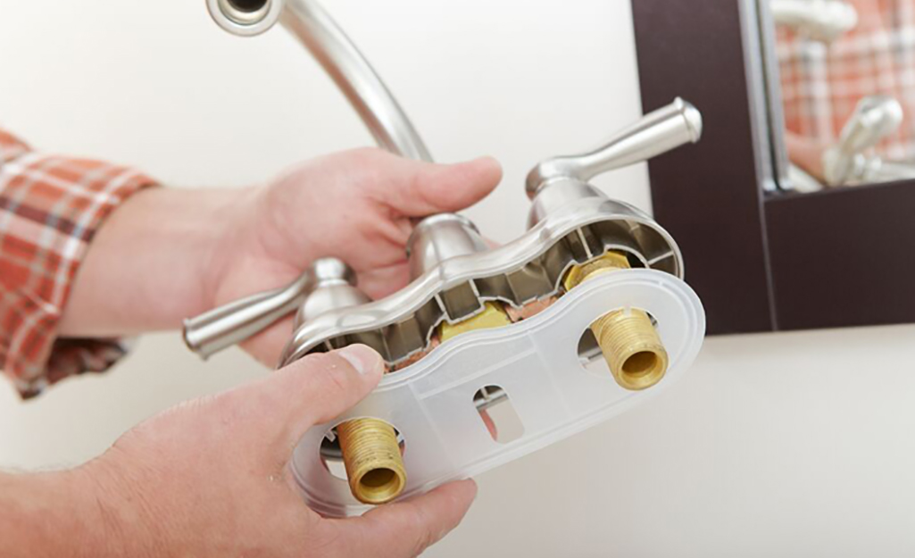 A person assembling a bathroom faucet before installing it on a sink.