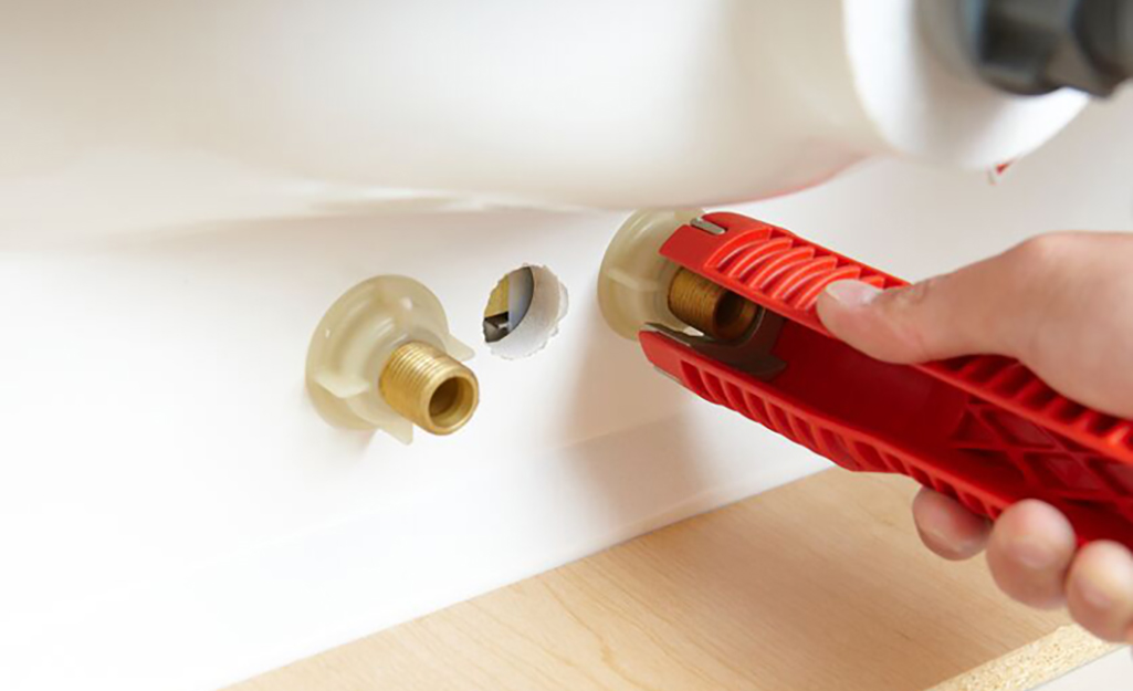 A person using a sink installing tool to tighten basin nuts for a bathroom faucet.