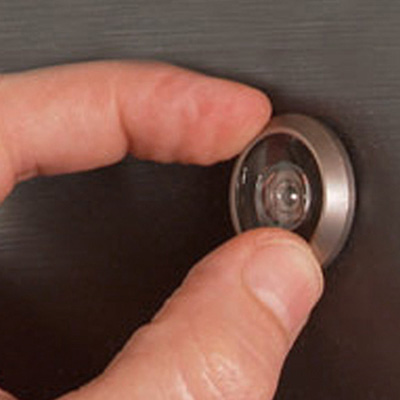 A person installs a peephole in a door. 