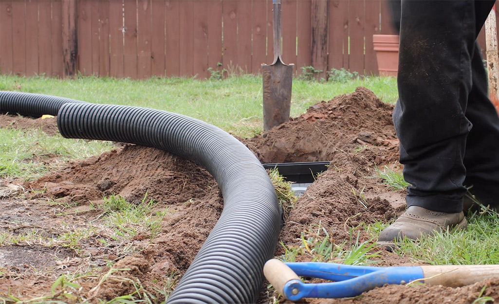 French drain pipe partially laid in a trench.