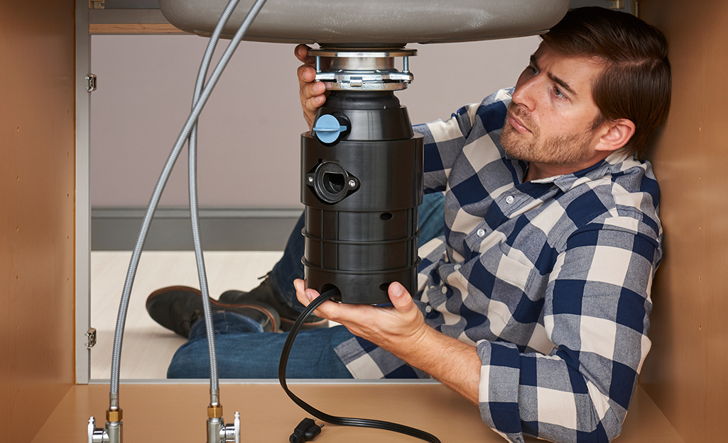 A person attaches a garbage disposal to a mounting ring,