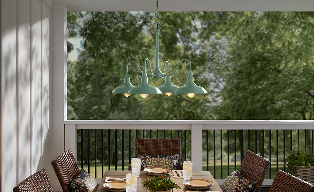An outdoor hanging light fixture over a patio set on a porch.