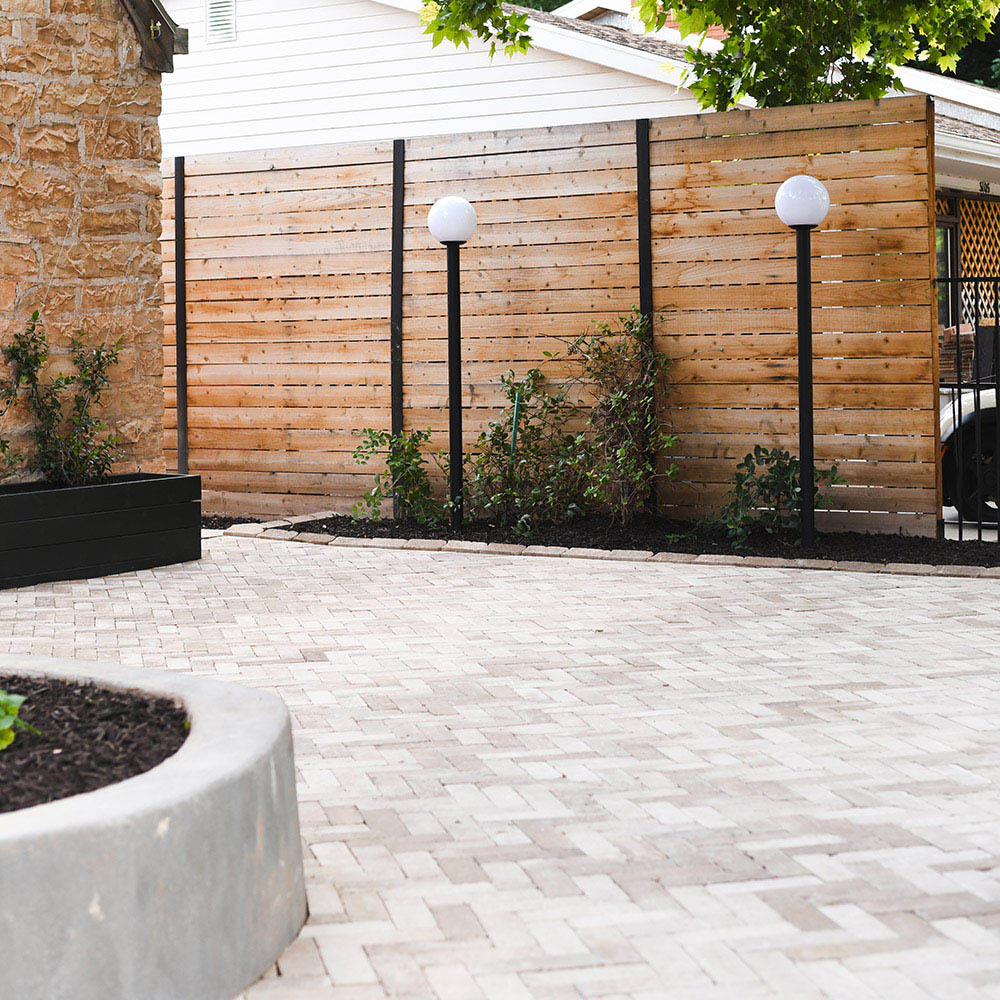 An outdoor area with paver, lights, and a privacy fence.