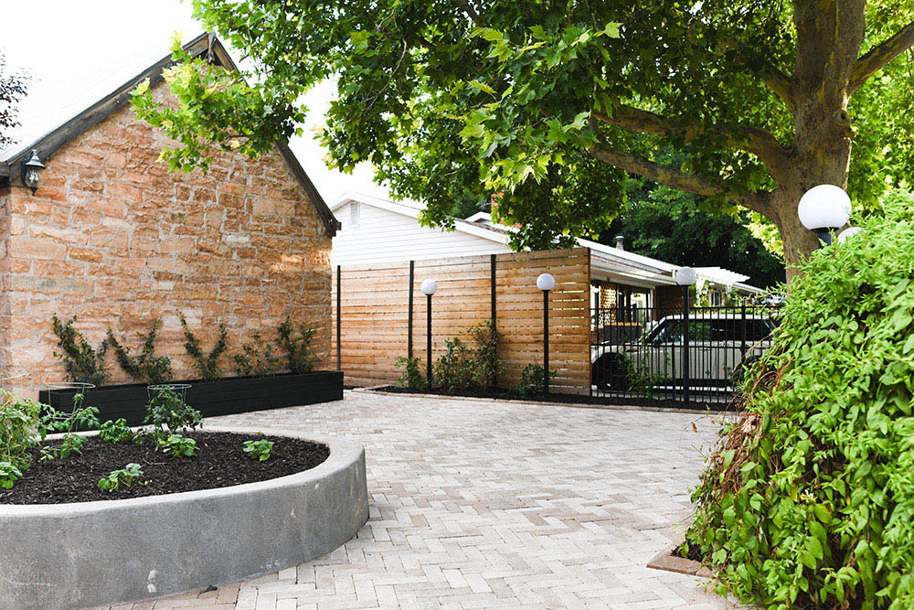 The outdoor area of a home with pavers and planter beds.