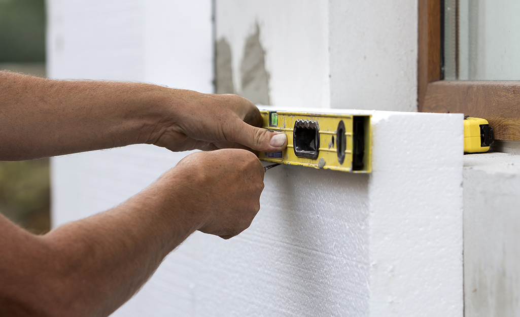 A person marking a wall with a level and pen.