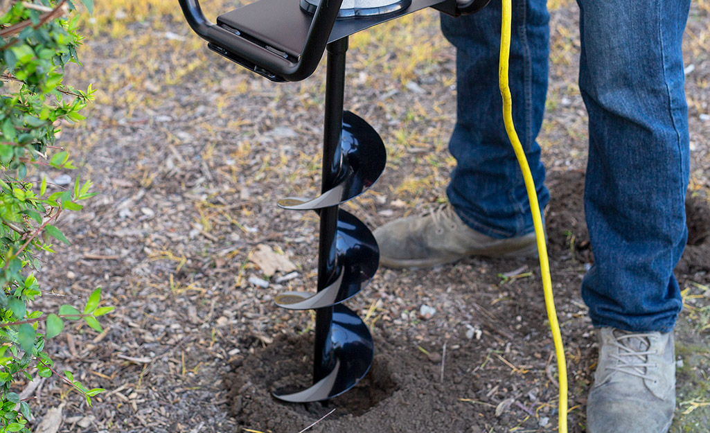 A person digging a hole for a post.