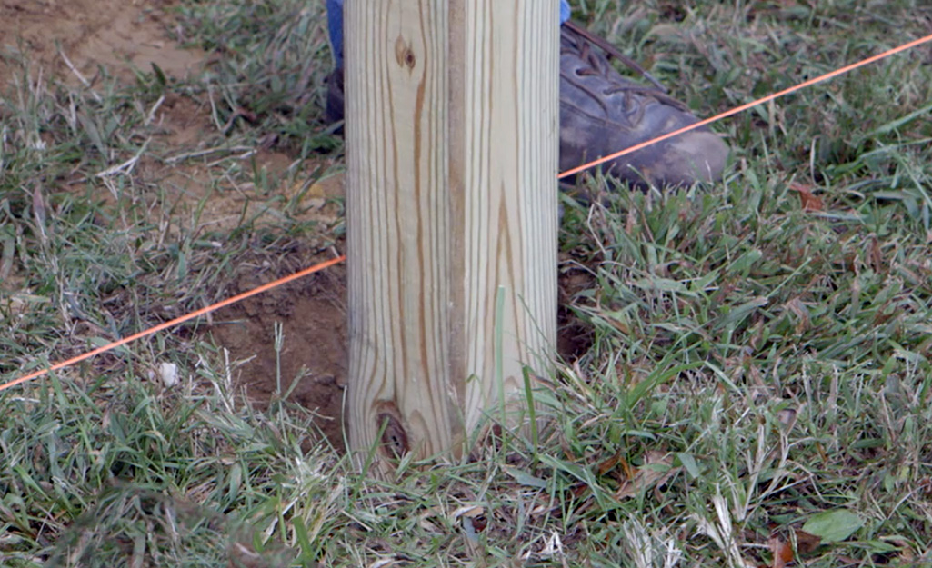 A person placing a mailbox post.