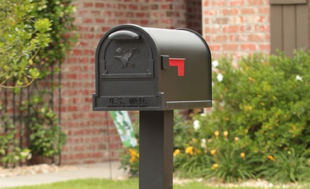 A brown mailbox attached to a mailbox post.