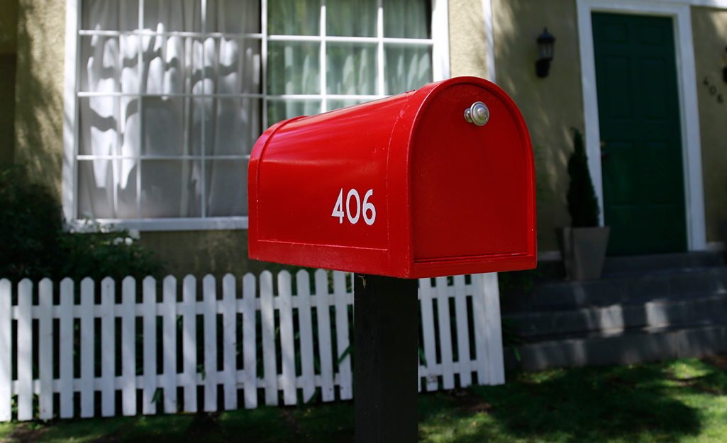 A red mailbox with white street numbers.