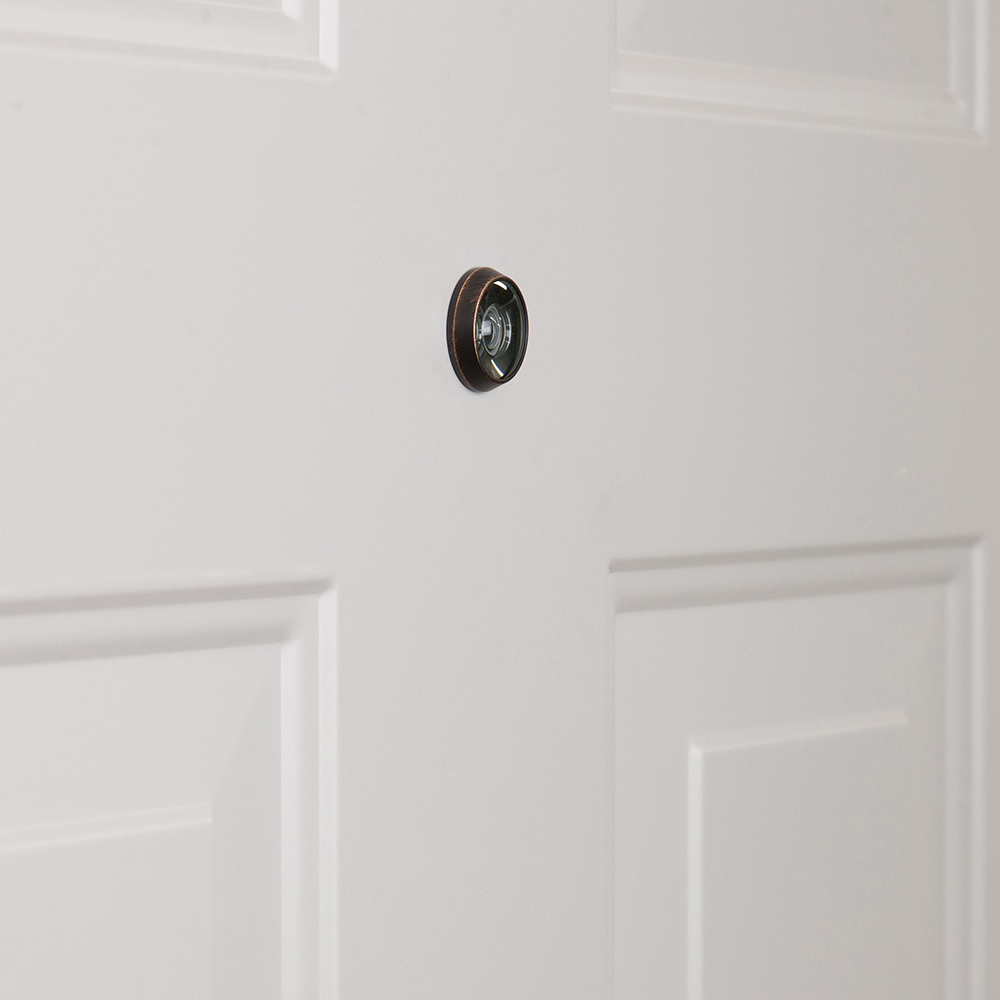 A peephole, or door viewer, installed in a steel entry door on a home.