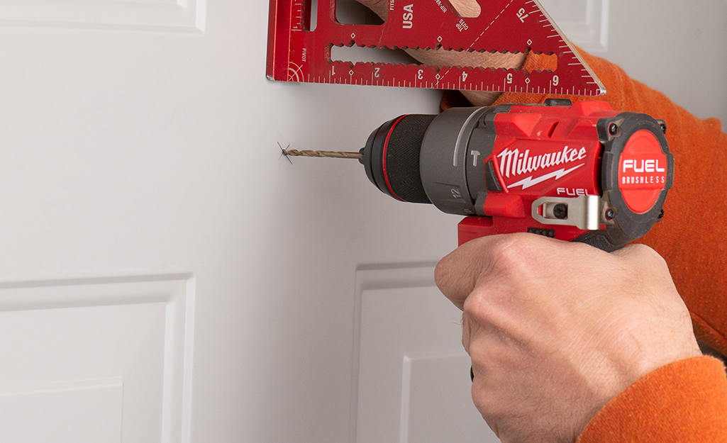 Drilling the pilot hole with a power drill and a rafter square.