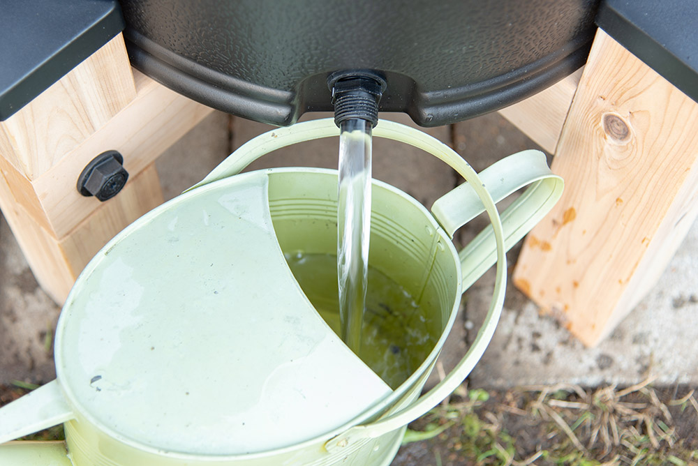 Water from a rain barrel fills up a green rain can.