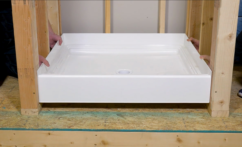 Two people test-fitting a shower pan.
