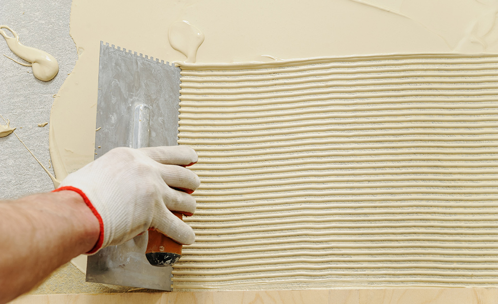 A person using mortar to level a subfloor.