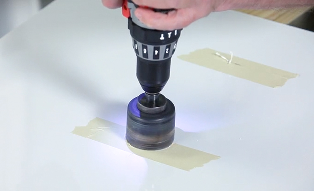 Man using a saw to cut fixture openings in a shower surround panel. Man using a saw to cut fixture openings in a shower surround panel.