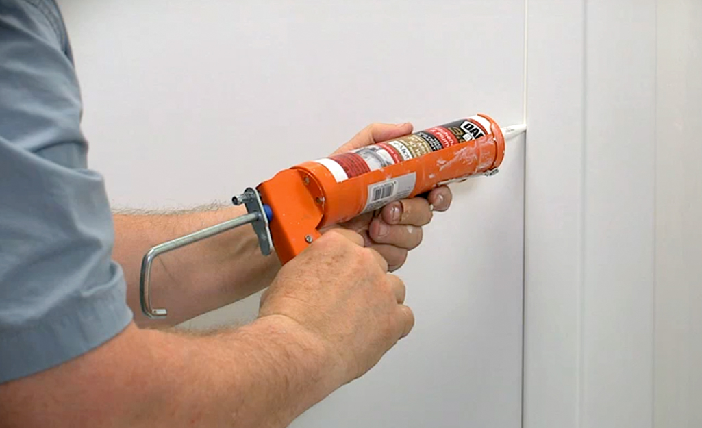 A man caulking the seams in a new shower surround. A man caulking the seams in a new shower surround.