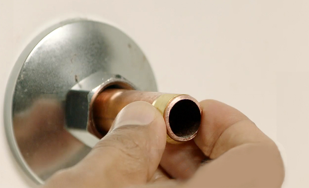 A person places a compression ring over a copper supply pipe.