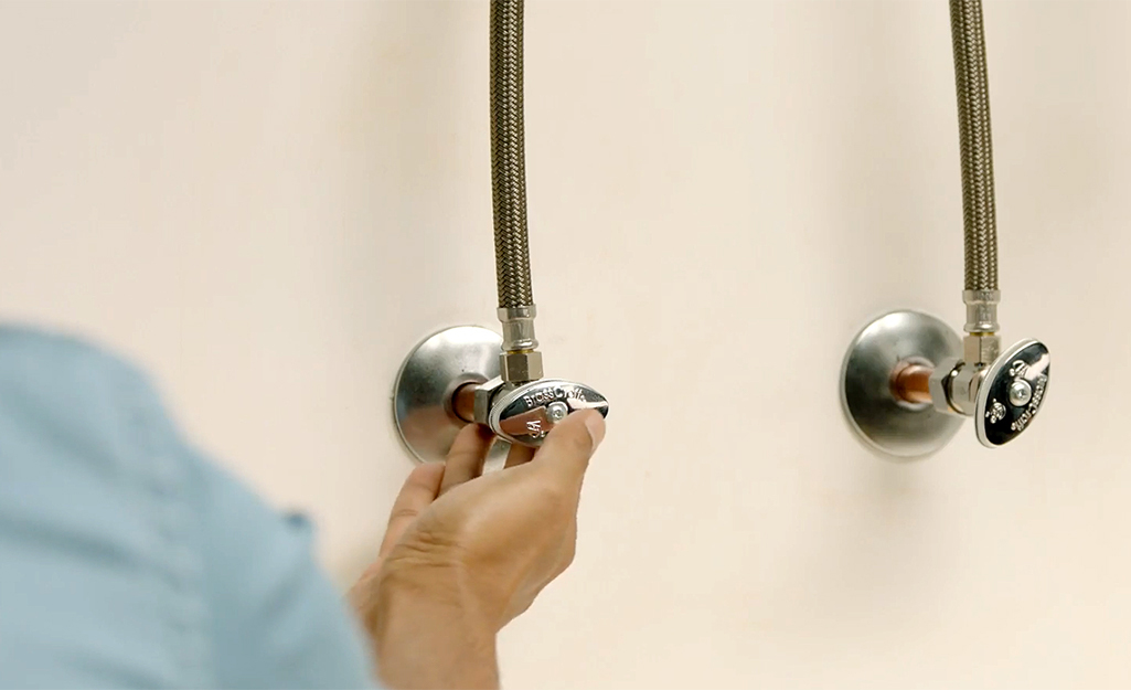 A person turns the knob on a shut-off valve.