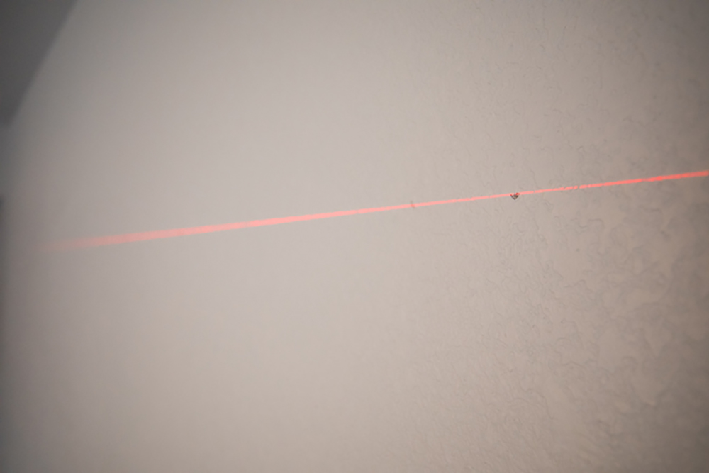 A laser level being used on a wall