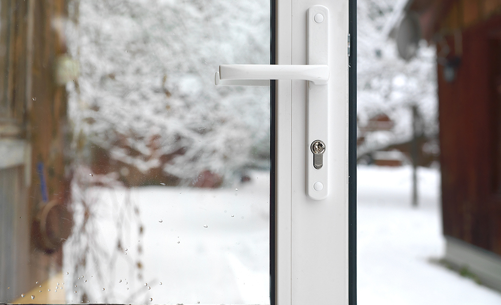 A storm door installed on a home with snow in the yard.