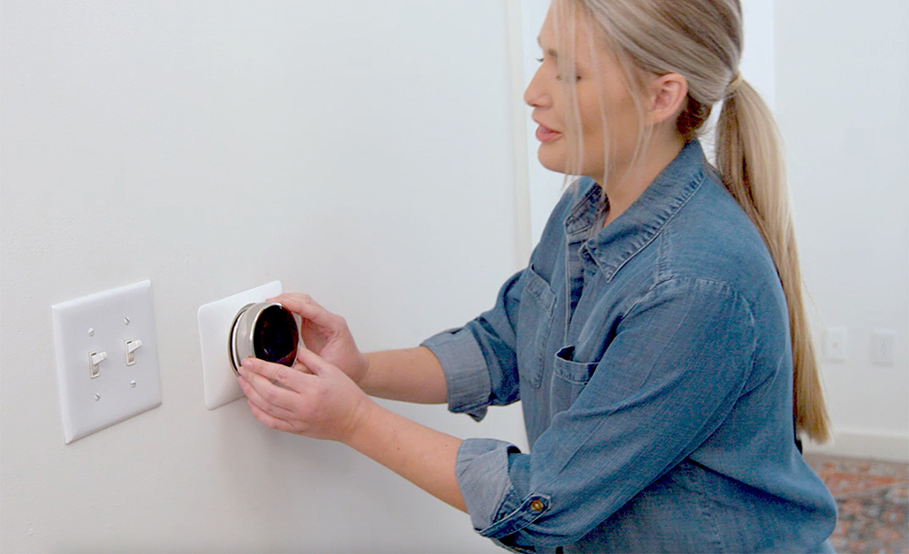 Woman adding face plate to programmable thermostat.