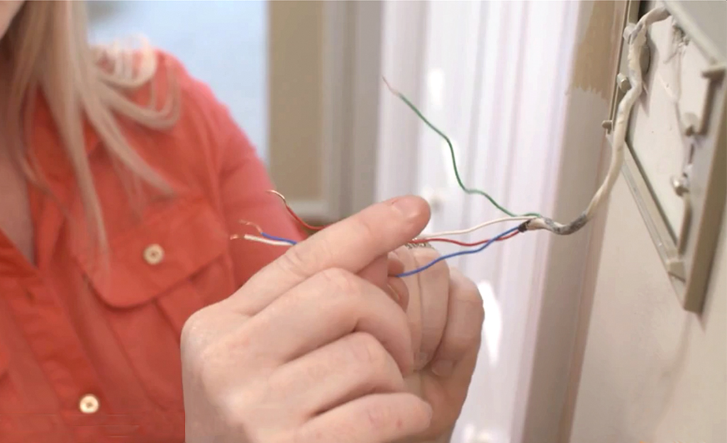 A woman separating thermostat wires.