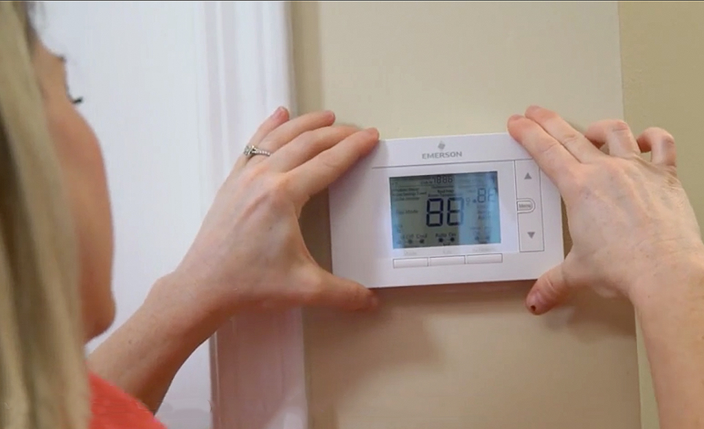 Woman adding face plate to programmable thermostat. Woman adding face plate to programmable thermostat.