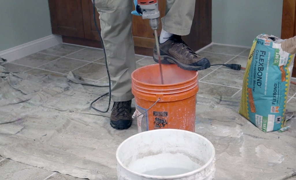 A person pouring water into an orange bucket. A person pouring water into an orange bucket.