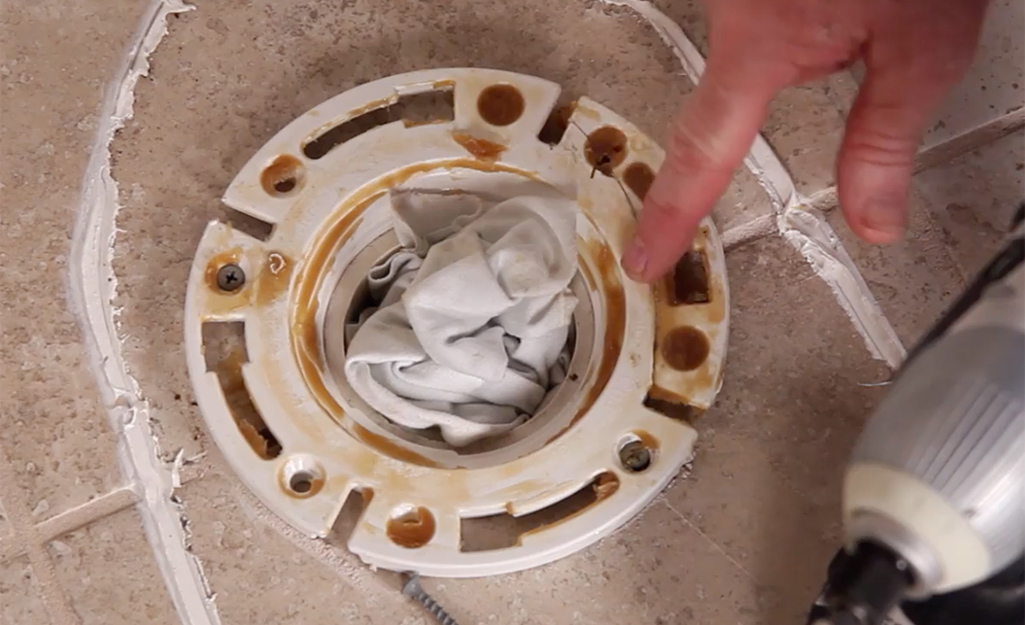 A person checks the condition of a toilet flange. 