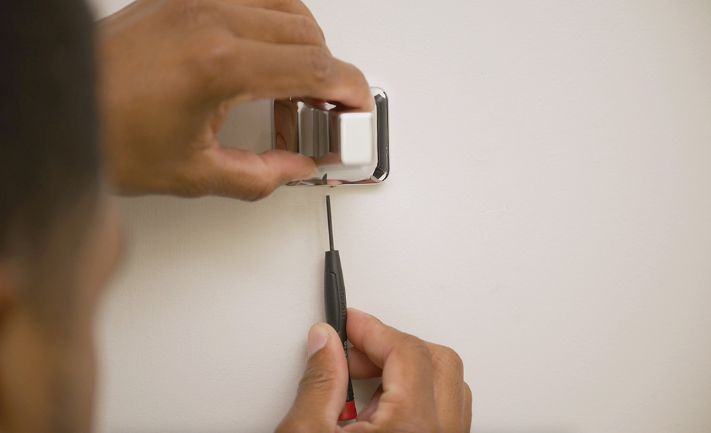 A person screwing a towel bar post to a bracket.