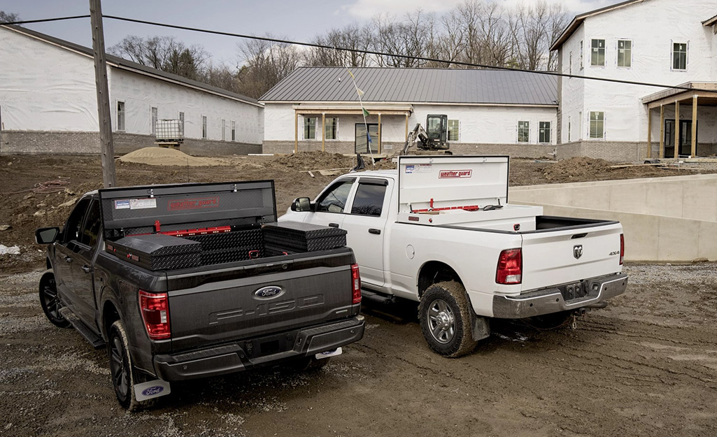 Two trucks with truck tool boxes park stand next each other.