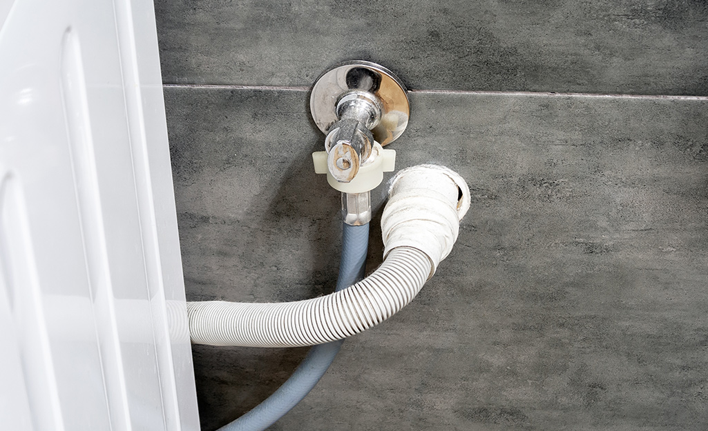 A washing machine drain hose installed in the wall.