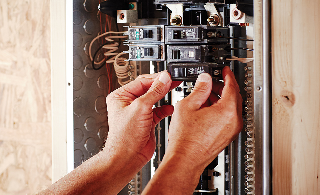 A person removing an old circuit breaker. 