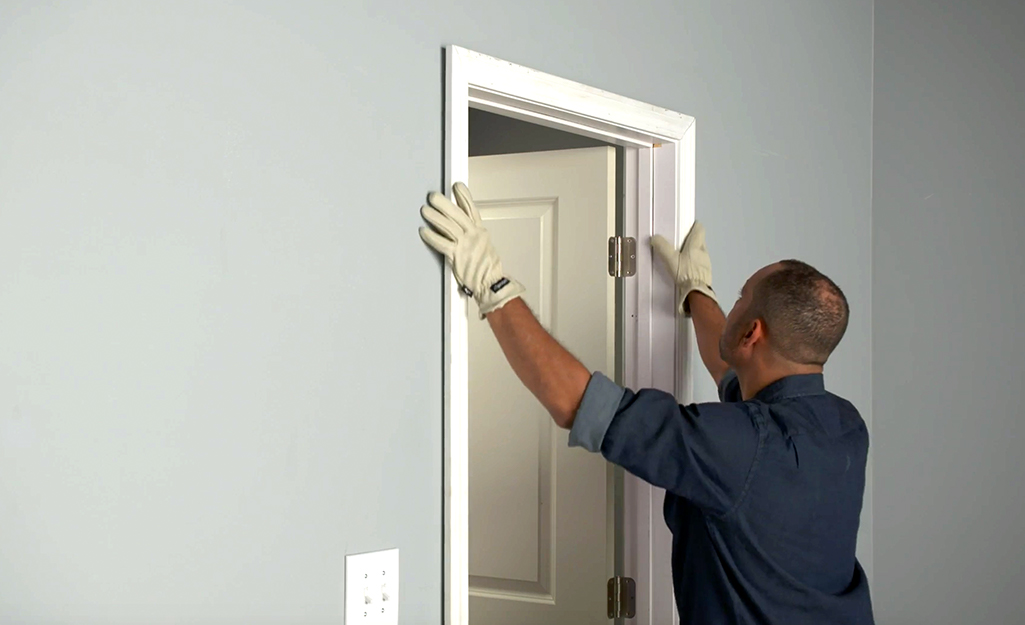 A man positioning door trim to a door.