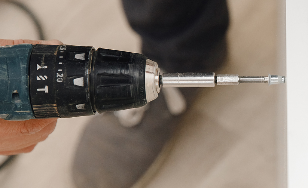 A person uses a drill to countersink pilot holes.