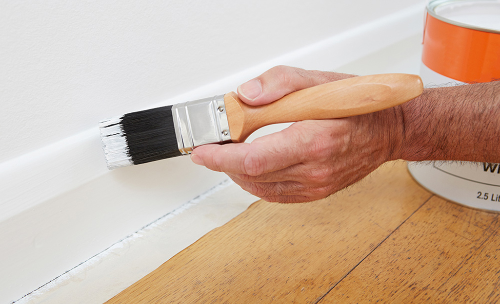 A person painting baseboard trim.