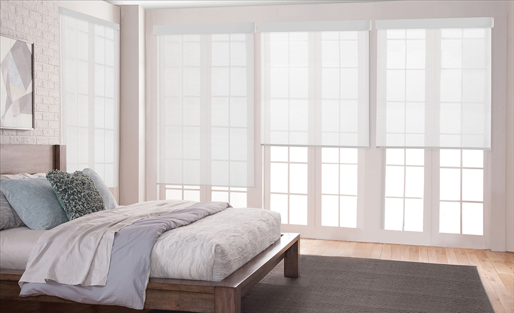 Sheer shades on windows in a bedroom.