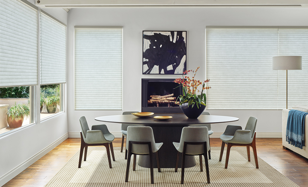 A dining room with windows covered by cellular shades mounted outside the window casings.