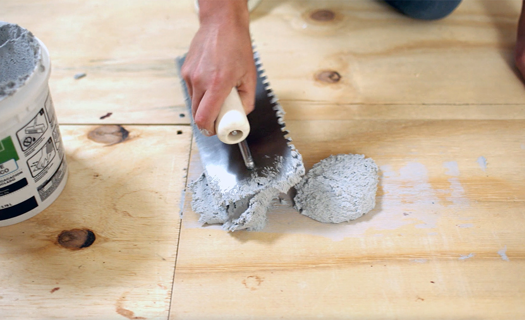 A person spreads mortar on the floor before laying cement backerboard is installed.