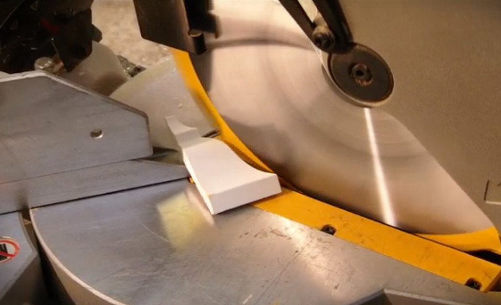 Person making cuts in moulding with miter saw.
