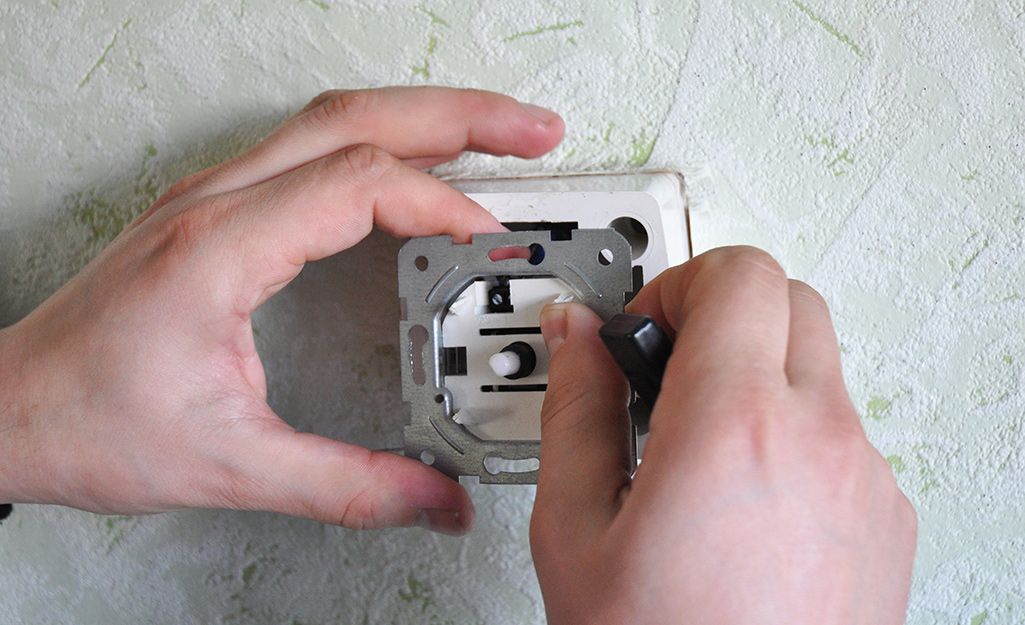 A person removing an old switch.