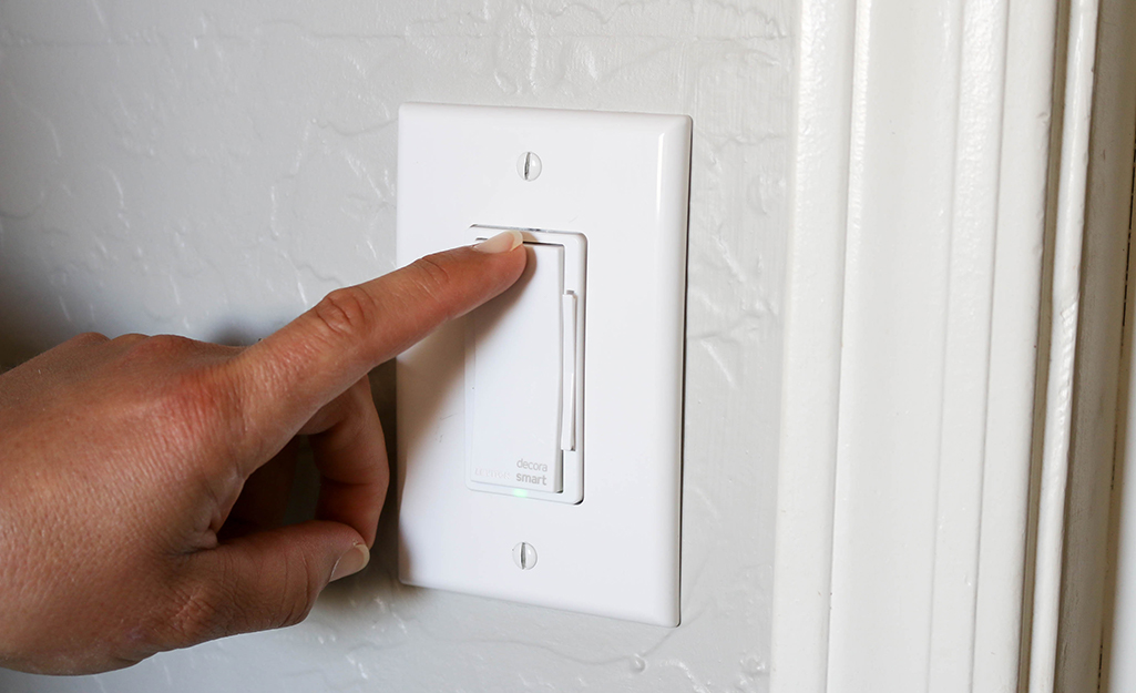 A person touches the dimmer switch to test the power. 