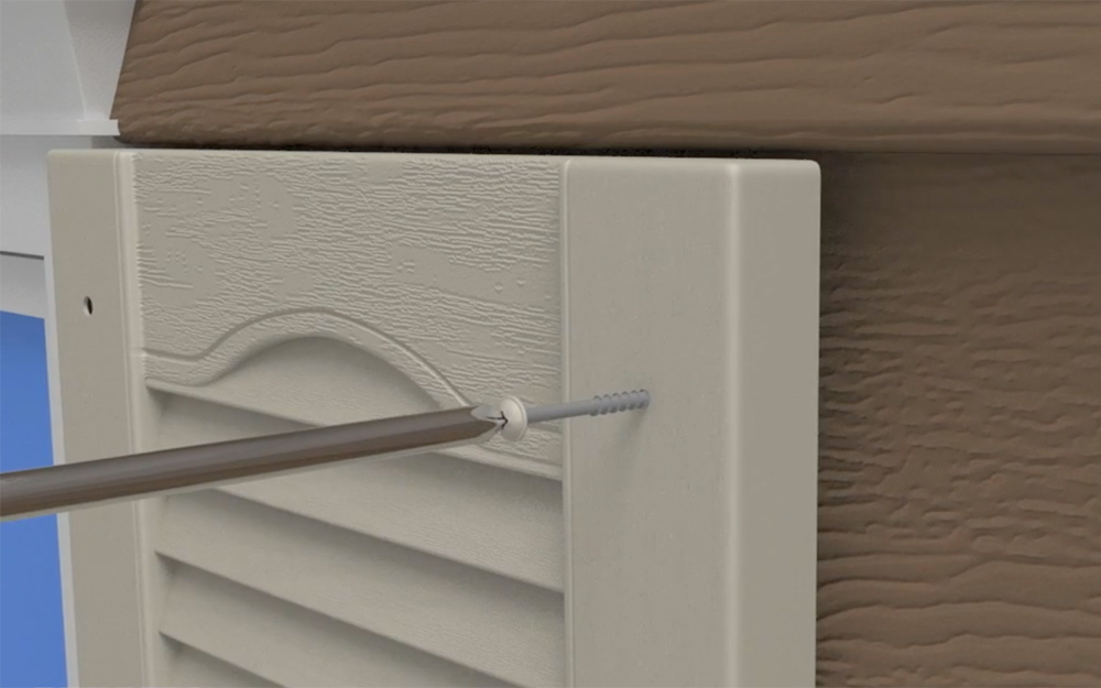 A screwdriver tightens a screw to install an exterior shutter.