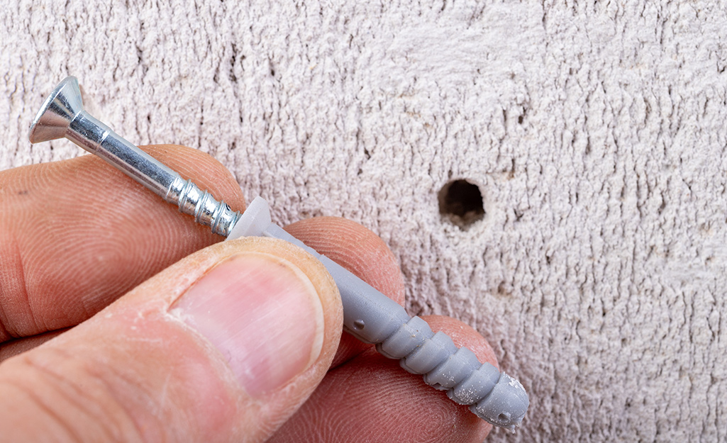 A person installs drywall anchors. 