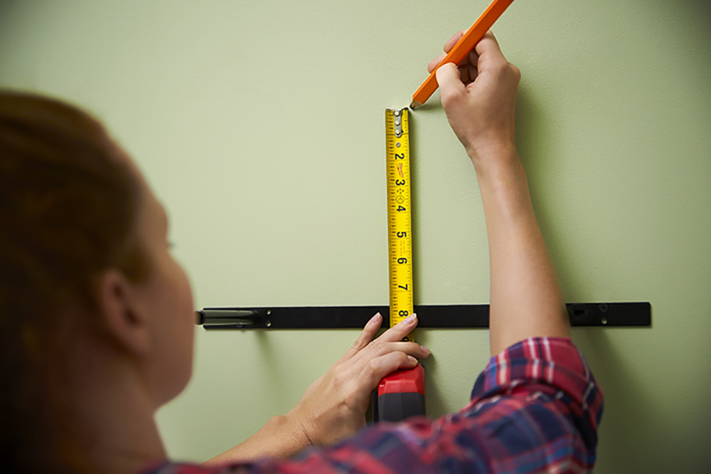 A person using a tape measurer to determine shelf placement.